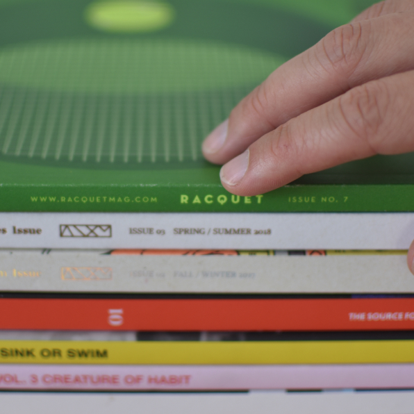 An image of a hand resting on top of a stack of books focused on creativity and design. 
