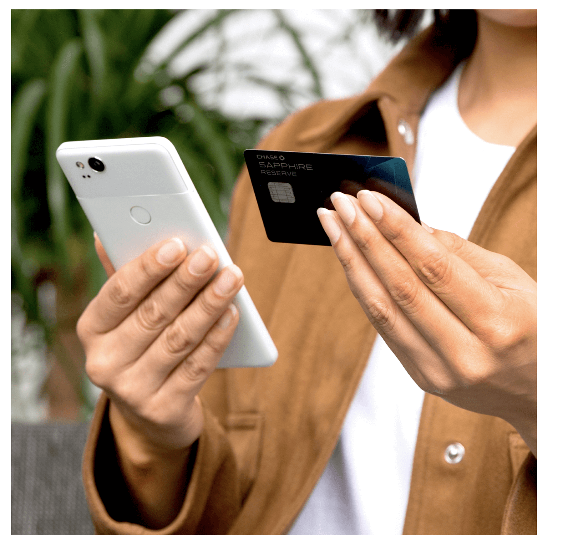 An image of a woman in a white shirt and brown jacket using their phone to add their debit card to the Google Pay app.